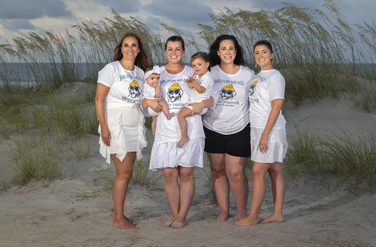 Group of women and children in matching Hilton Head shirts posing on the beach during a family vacation session