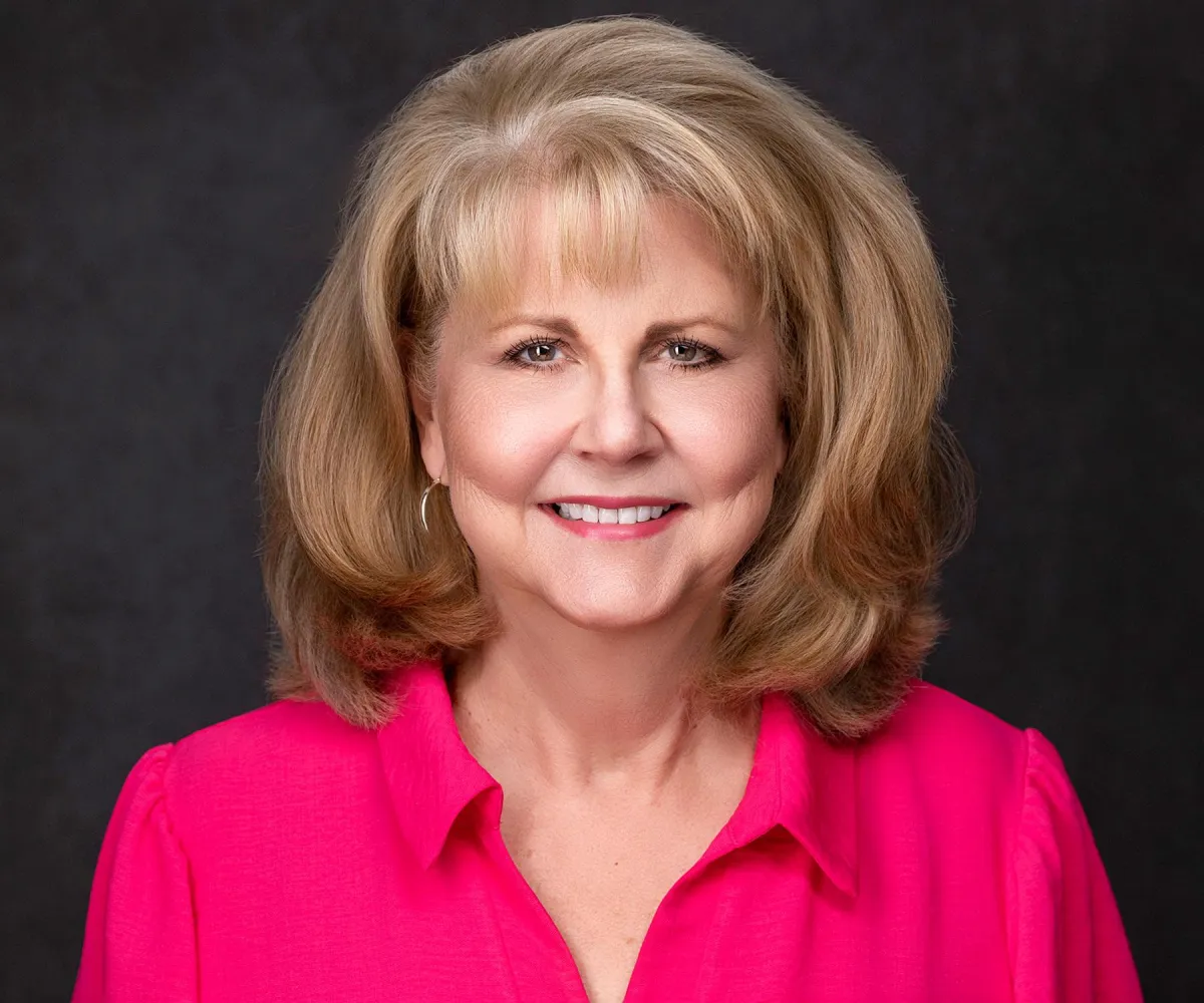 Professional studio headshot on light gray — sharp focus, flattering light.