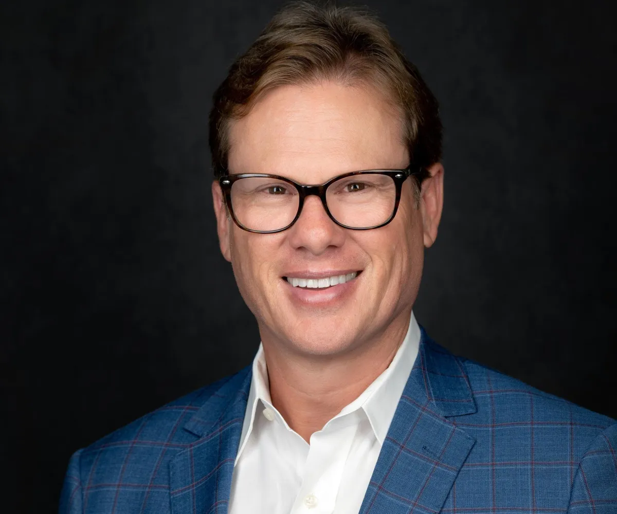 Modern headshot on slate backdrop — subtle angle, relaxed smile.