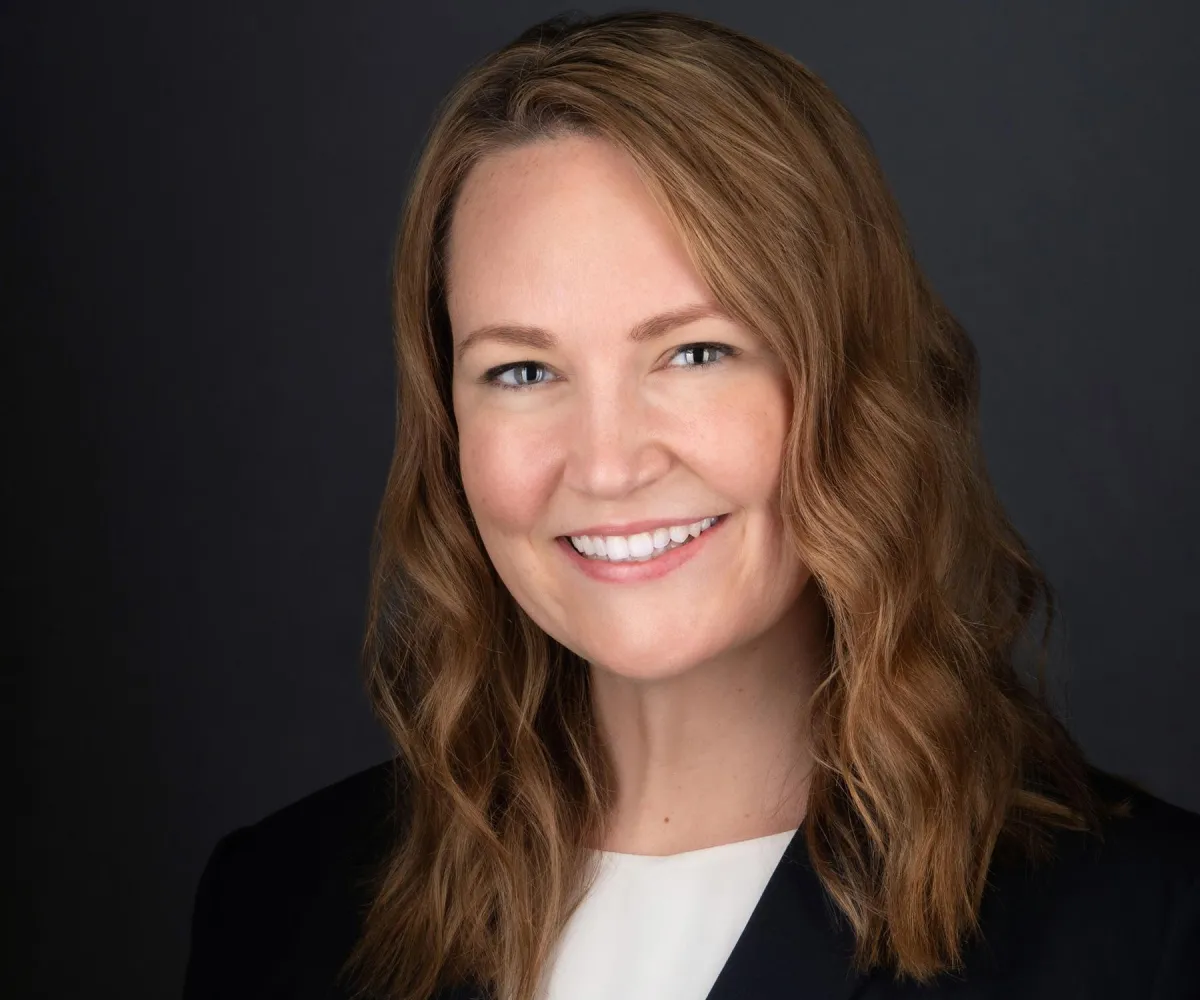 Professional headshot with charcoal background — studio lighting, approachable expression.