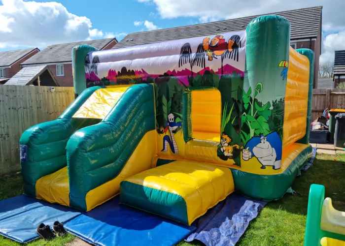 Jungle inflatable bouncy castle and slide in a back garden