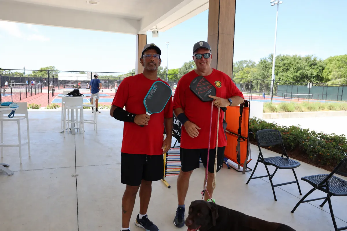 Two pickleball players standing near outdoor courts with paddles and BFX Stretch equipment.