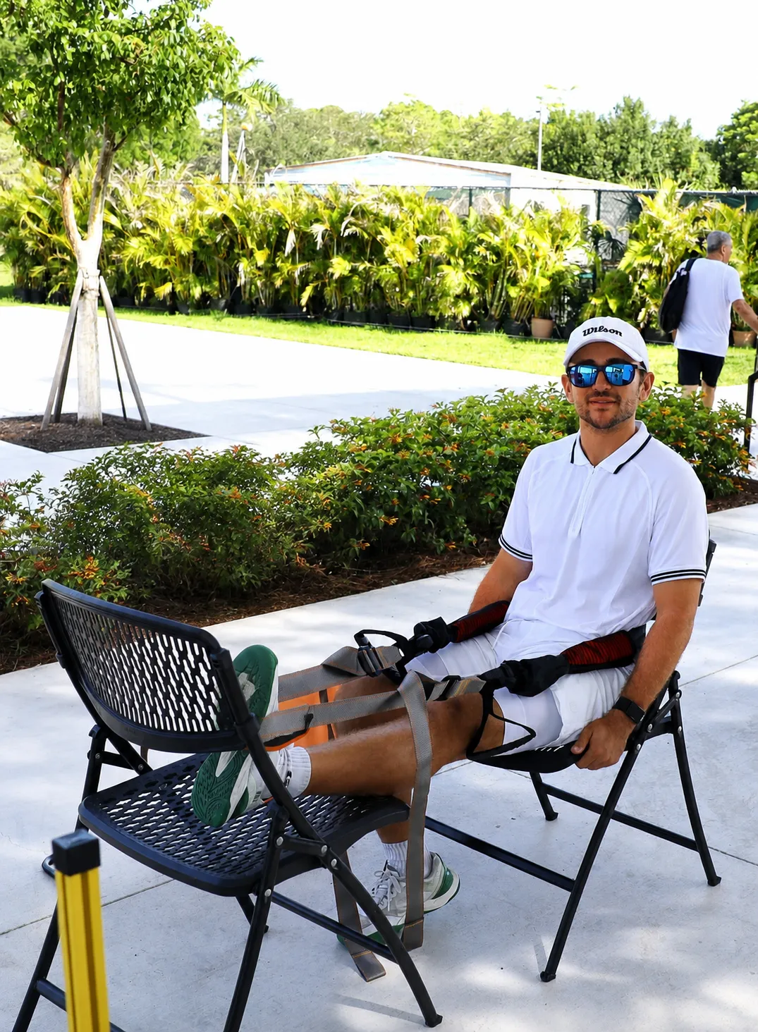 Pickleball player seated court-side using BFX Stretch with one leg extended.