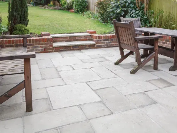 A tidy and freshly cleaned patio area with wooden furniture and a garden backdrop.