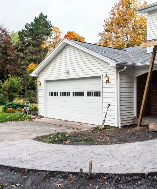 White garage door on a suburban home during fall with stamped concrete path