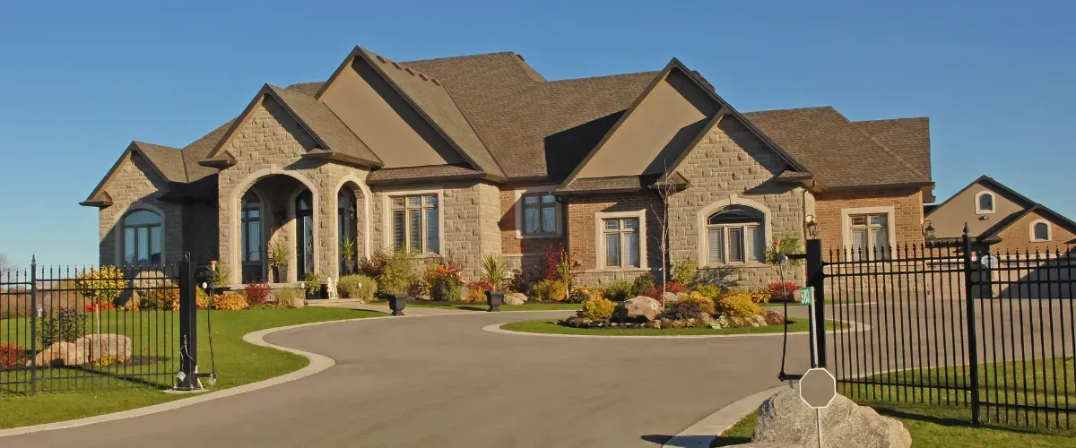 Spacious luxury home with stone exterior and a circular driveway in front