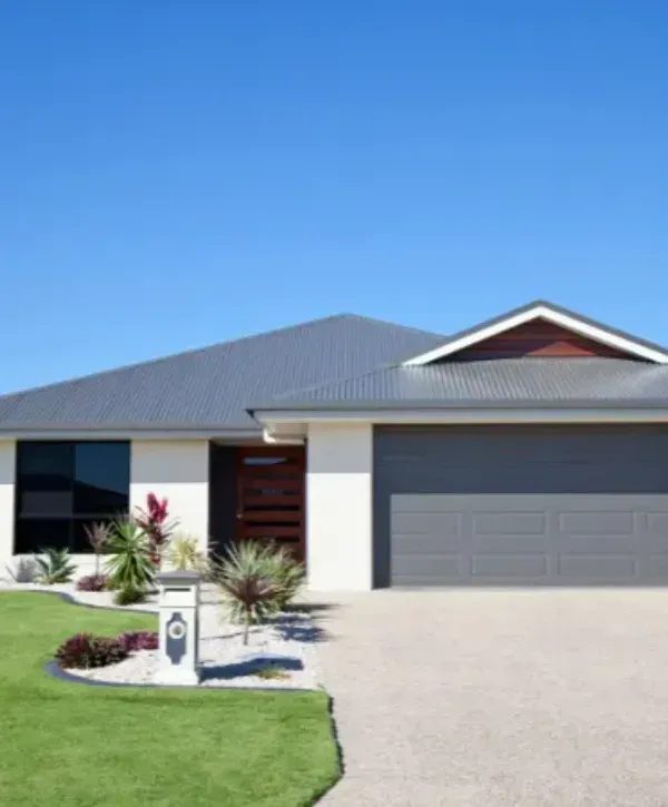Modern home with a gray garage door, manicured lawn, and minimalist landscaping.