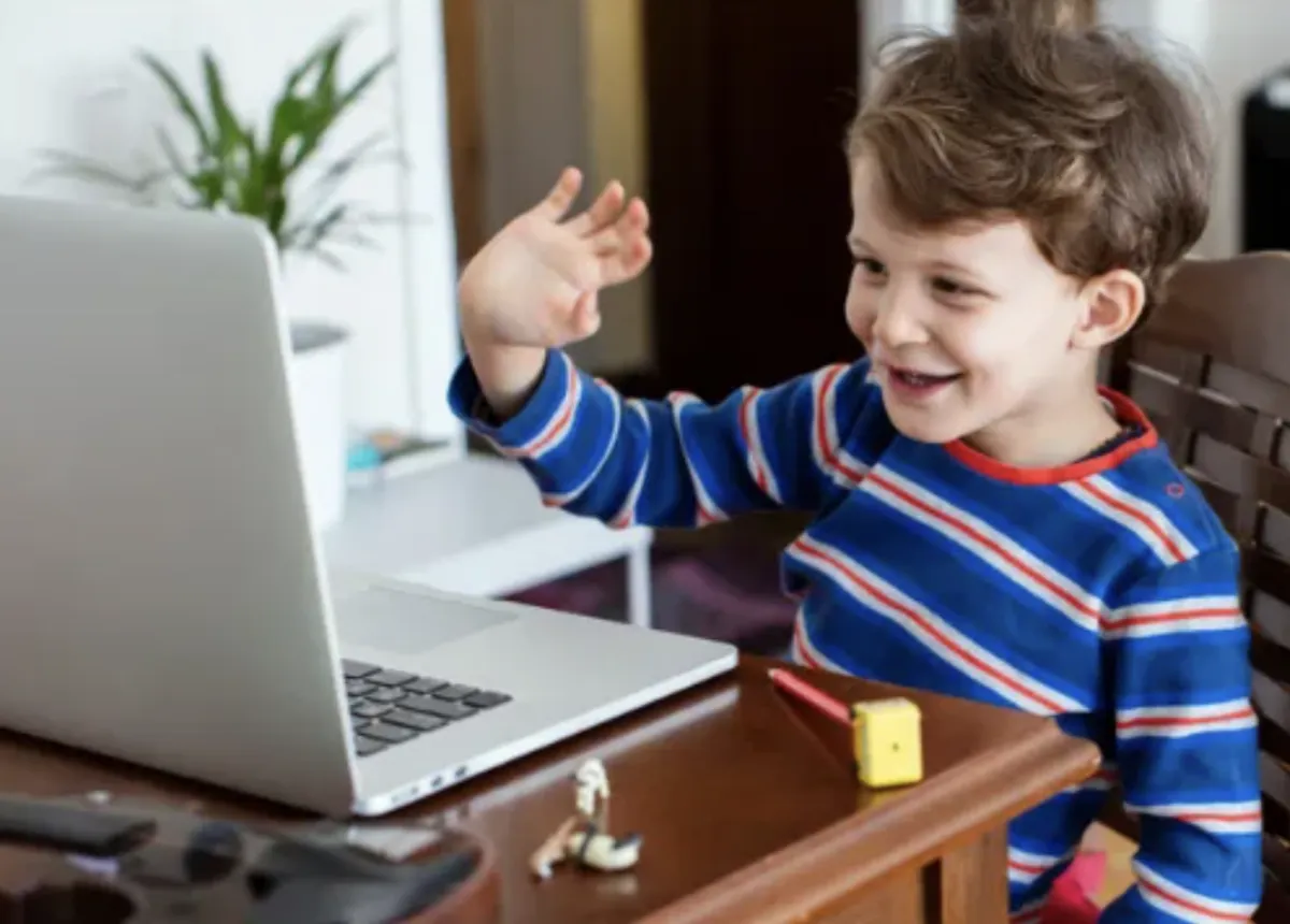 Child waves at laptop