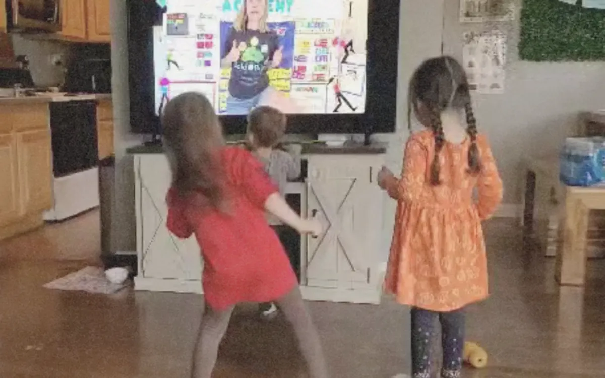 Kids moving with the teacher on a large screen TV