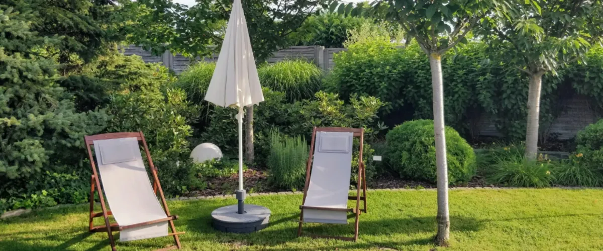 Two lounge chairs and umbrella in a peaceful garden backyard setting.