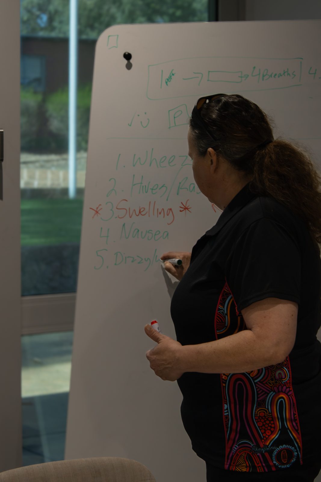 Britt Brennan writing an anaphylaxis symptom checklist on a whiteboard