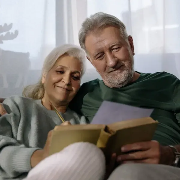 retired couple sitting on a sofa together smiling