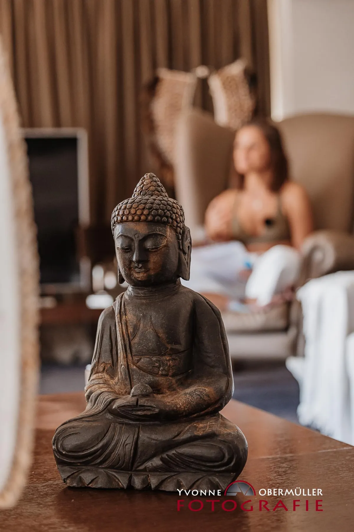 Achtsame Atmosphäre beim Shoot & Shine Event: Detailaufnahme einer Buddha-Statue mit Coaching-Teilnehmerin im Hintergrund.