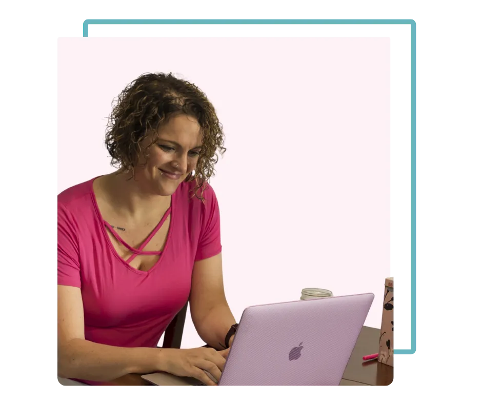 Mandy McGowan smiling in a pink shirt using a computer