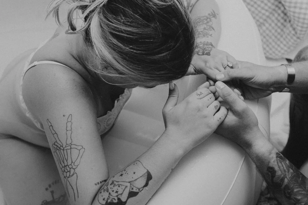 Laboring mother holding a support person's hand during home birth