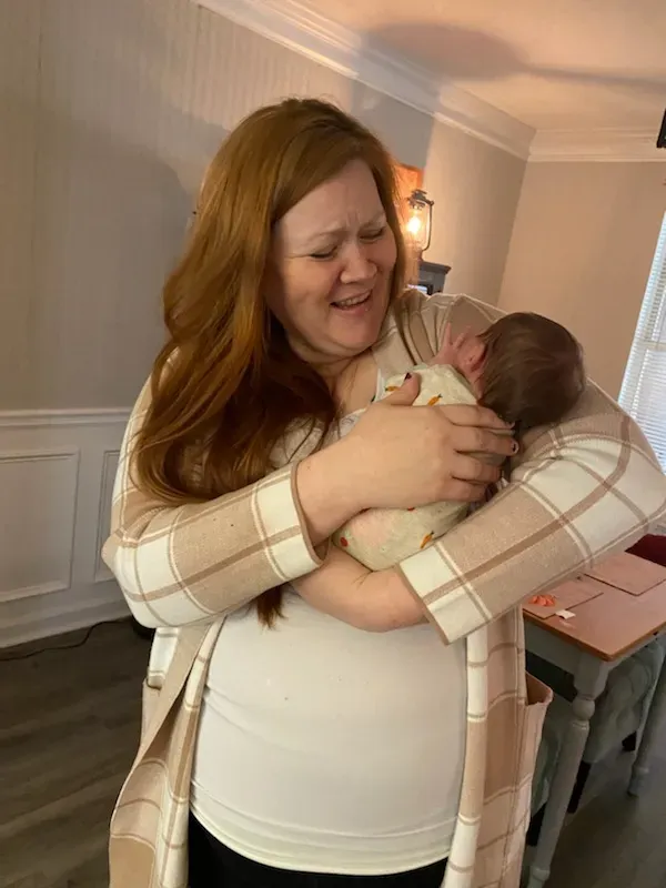 Birth support provider cradling a newborn baby after home birth