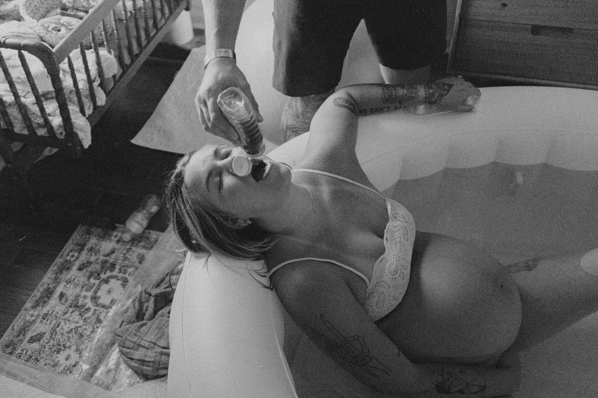 Laboring mother receiving hydration and support in a home birth pool