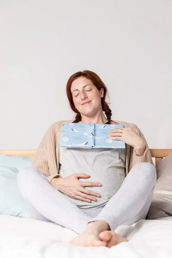 Pregnant woman relaxing with a book while preparing for birth at home in Warner Robins, GA