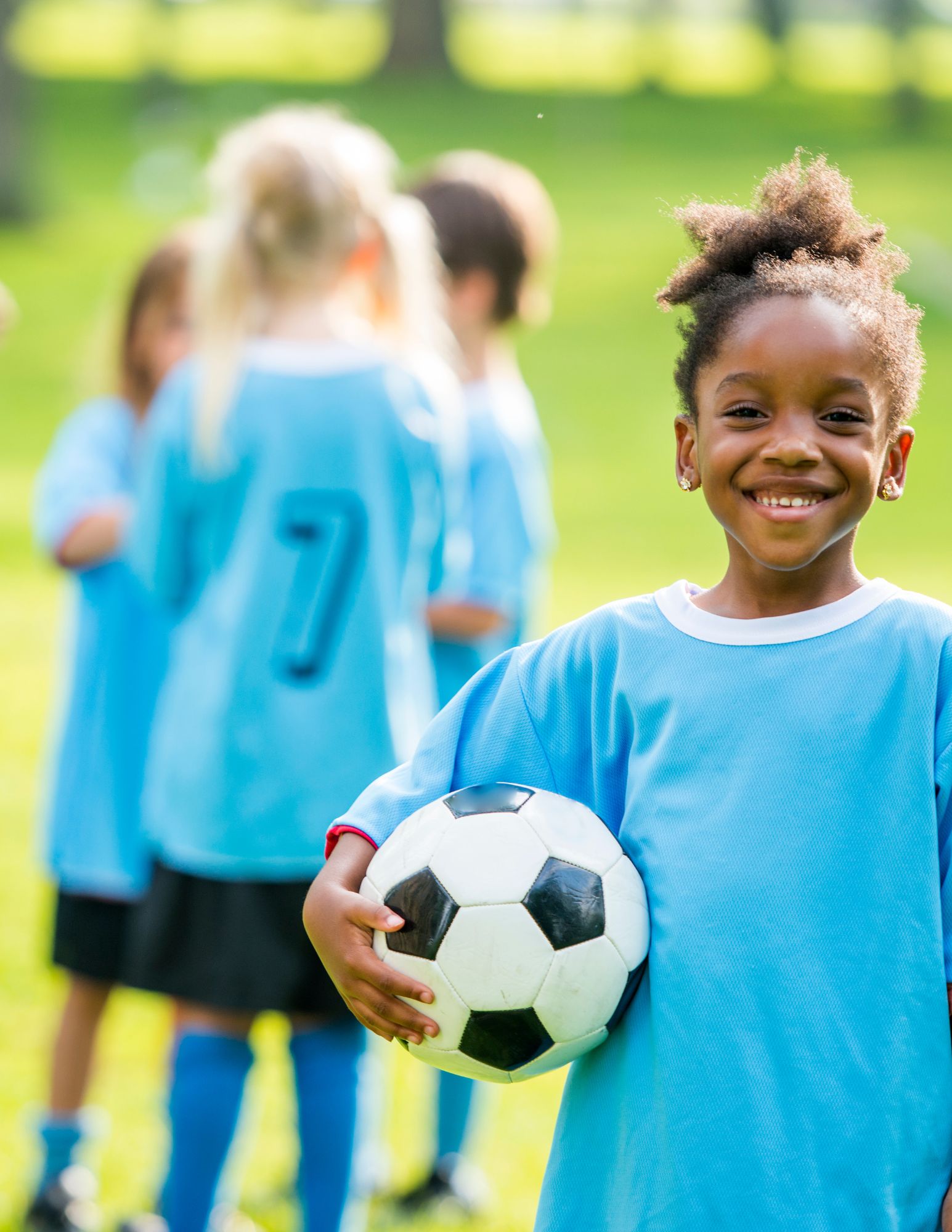 Child writes A in green sand