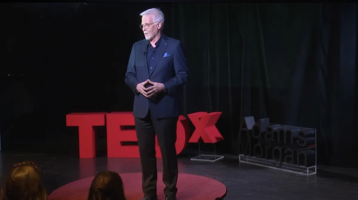 Professional lead-generation coach portrait, male, mid-40s, three-quarter composition with soft office blur behind, warm window light, approachable expression, wearing blazer, subtle grey hair, photorealistic, high-resolution, 1:1 aspect ratio.