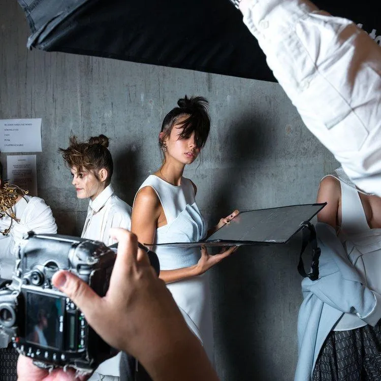 Woman backstage at a fashion show being photographed for fashion marketing and advertising.