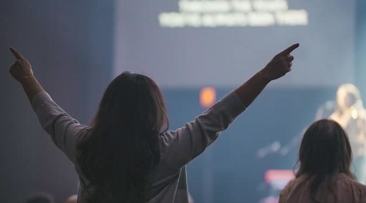 Warm, faith-filled moment of attendees in prayer, bathed in light