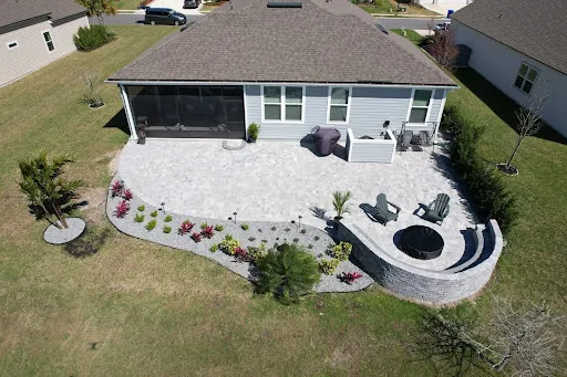 Aerial view of Buma’s paver patio with a curved fire pit seating area and landscaped beds