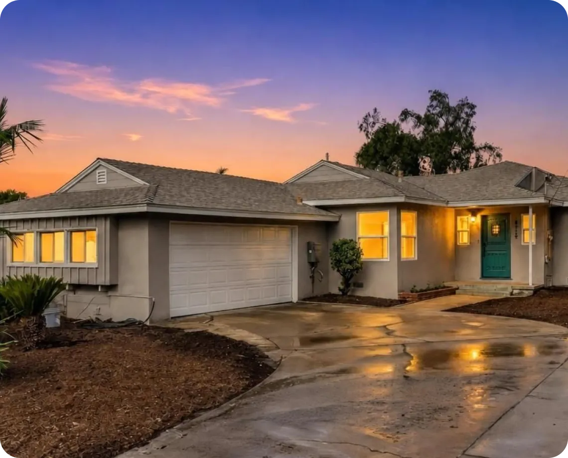 A modern single-story house at sunset, with a bright orange sky.