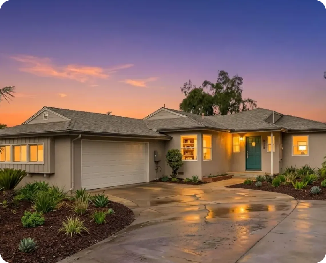 A modern single-story house at sunset, with a bright orange sky.