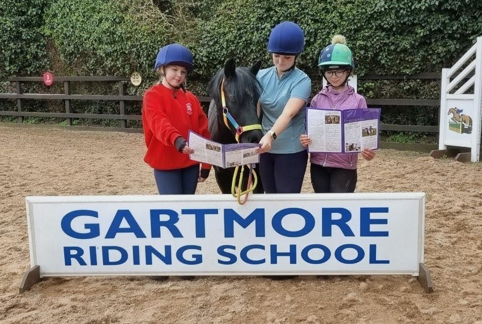 Three students standing with a pony