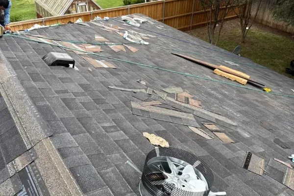 Roof shingle replacement in progress with tools and materials on a residential rooftop.