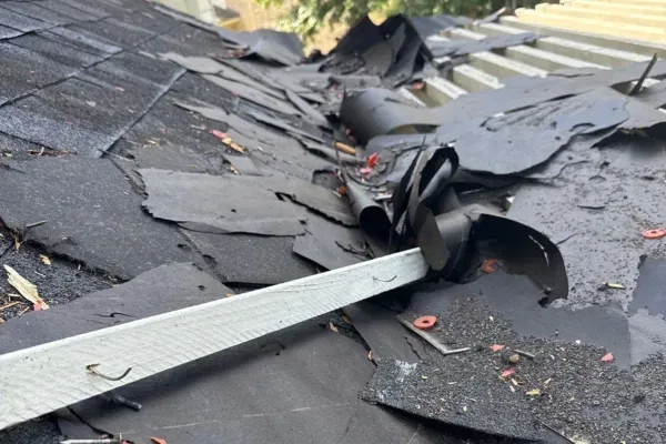 Old roofing materials and underlayment being removed during roof tear-off and preparation.