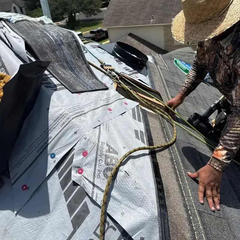 Roofer installing shingles over ABC Pro Guard 20 underlayment during roof replacement.