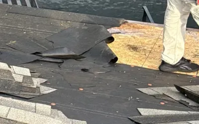 Roof repair in progress with old underlayment removal and new asphalt shingles ready for installation.