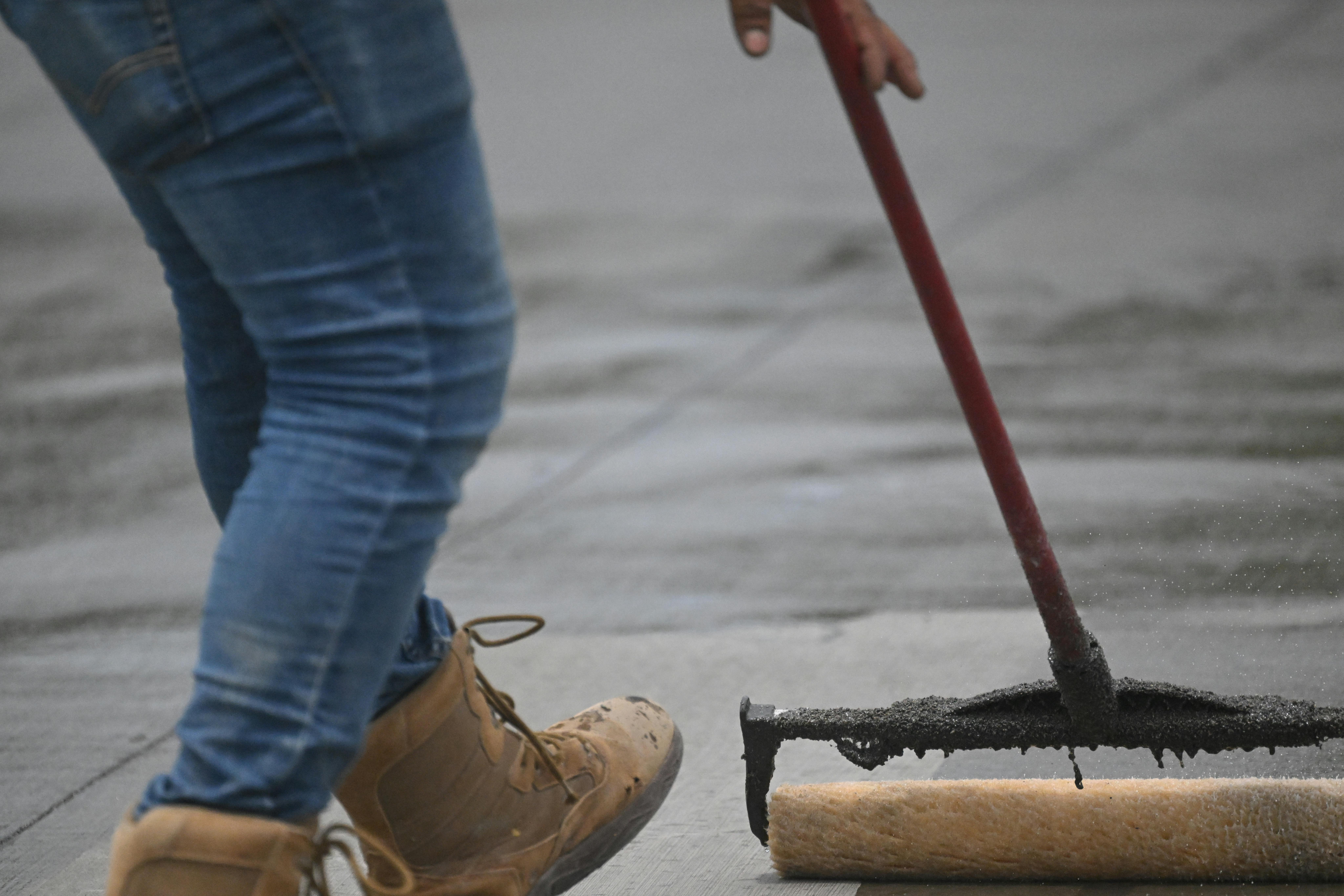 a man rolling a paint roller across a wet concrete floor