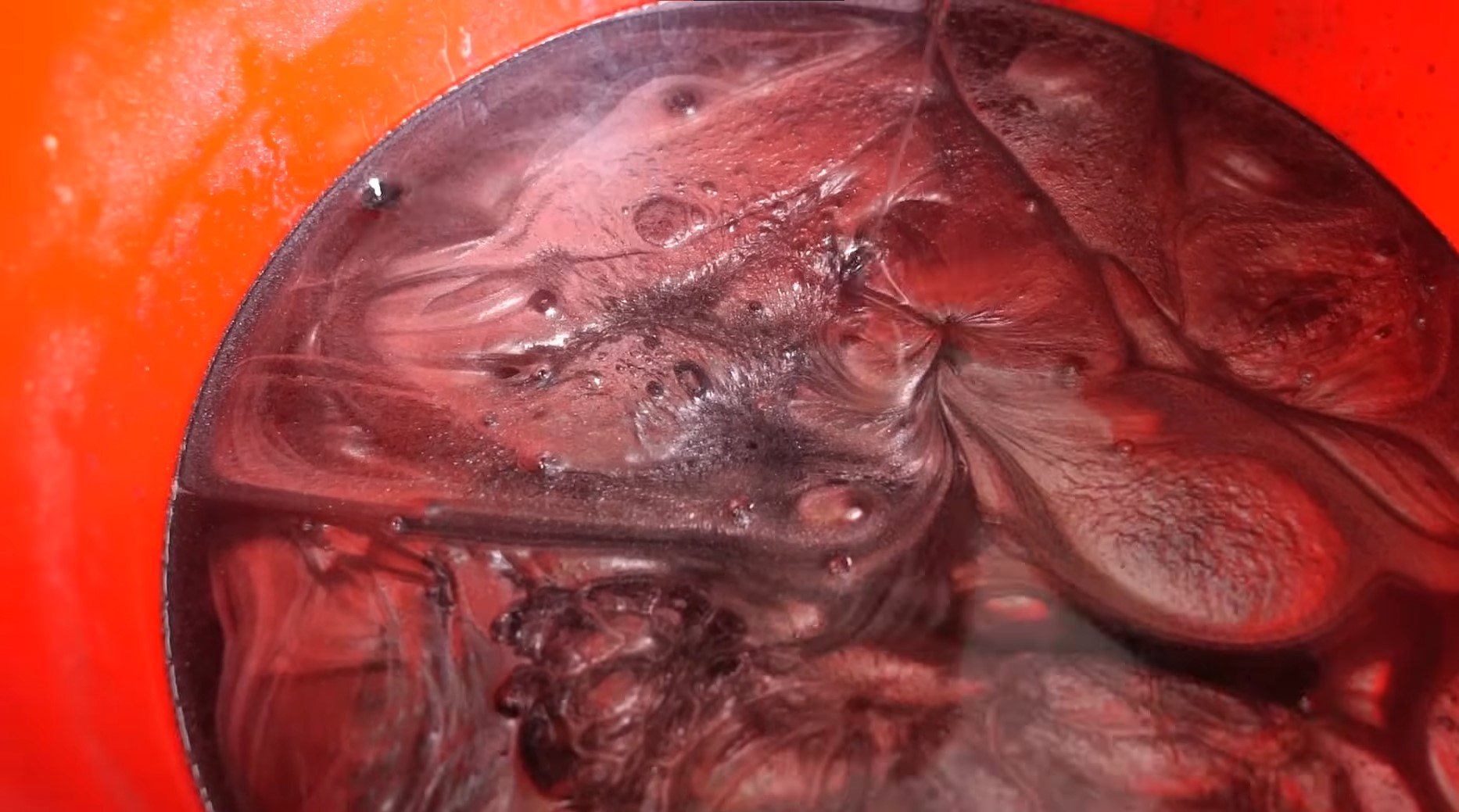 Inside of an orange bucket filled with a black silver metallic epoxy resin