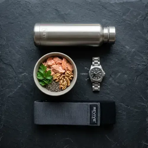 fitness essentials including a stainless steel water bottle, a bowl of salmon and walnuts, a wristwatch, and a grey resistance band