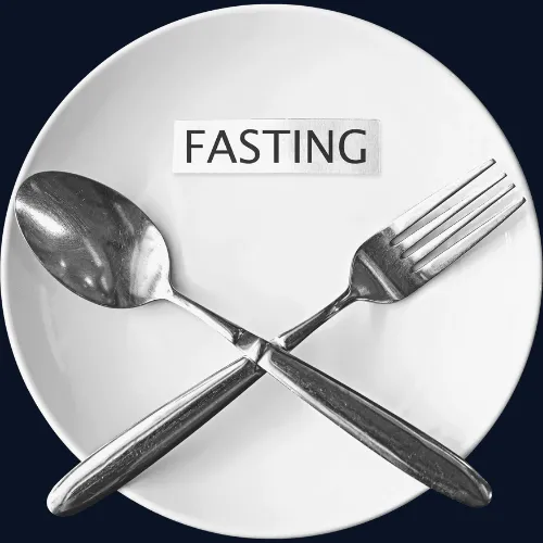 crossed spoon and fork resting on a white plate with a label "FASTING"
