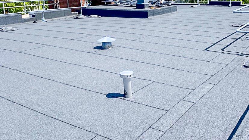 RoofNuts crew applying cap sheet to modified bitumen roof