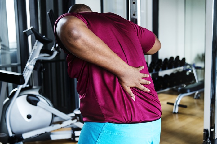 Man suffering from sciatica pain while playing sport at the gym