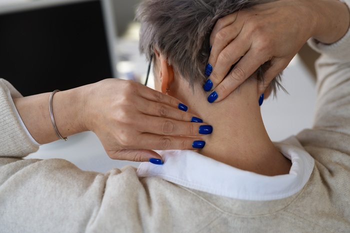 Women suffering from neck pain and squeezing it