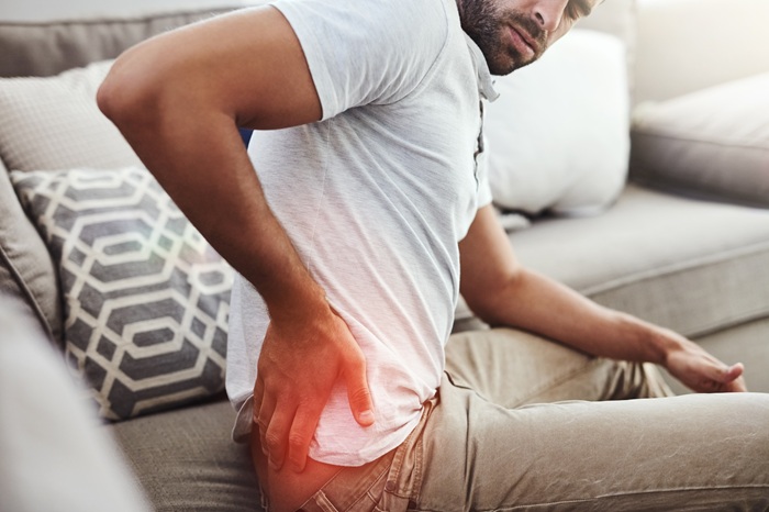 man suffering from hip pain while sitting