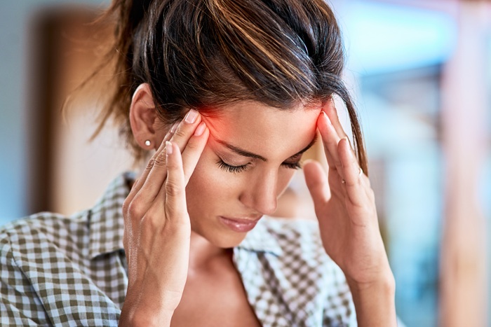 Women suffering from migraine and squeezing her head