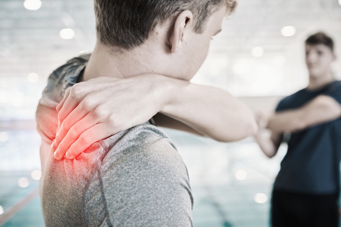 Young man suffering from shoulder pain while doing sport