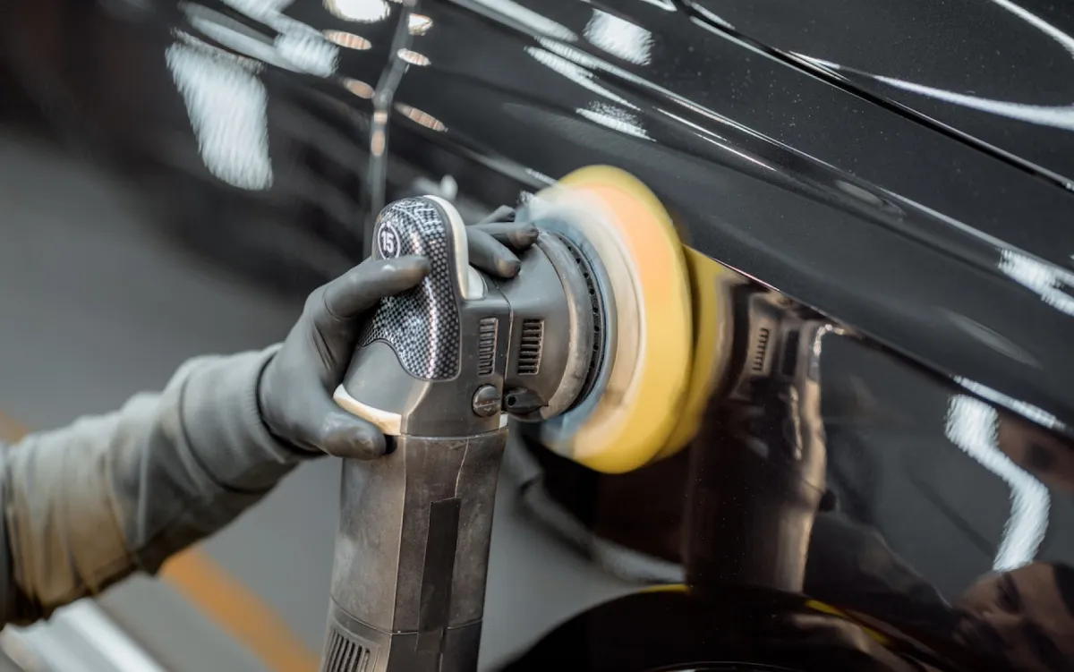 A person polishing the exterior of a car, enhancing its shine and appearance