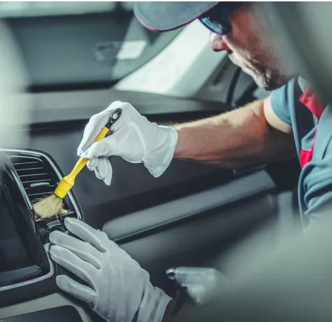 A man using a brush to clean the car air conditioning unit