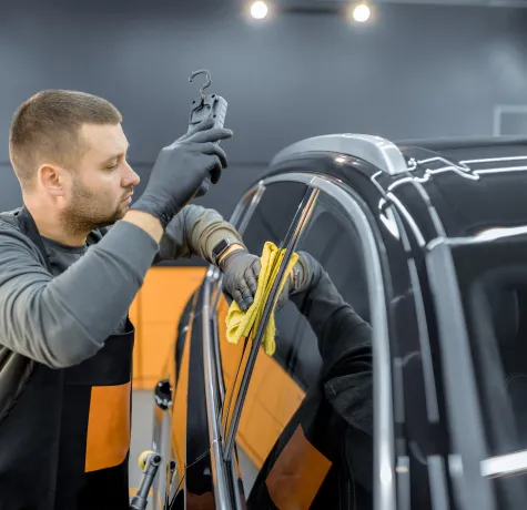 erson wiping a tinted window of a car with a cleaning cloth