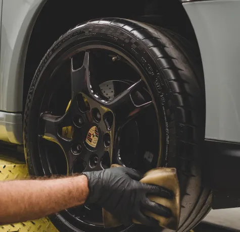 A person detailing and cleaning the automotive rim