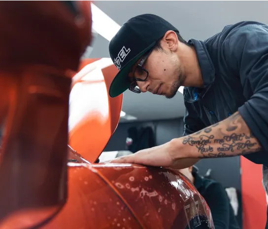 A man applying Paint Protection Film (PPF) to a car surface