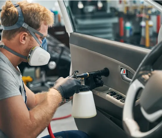 A man cleaning the interior side door of a car